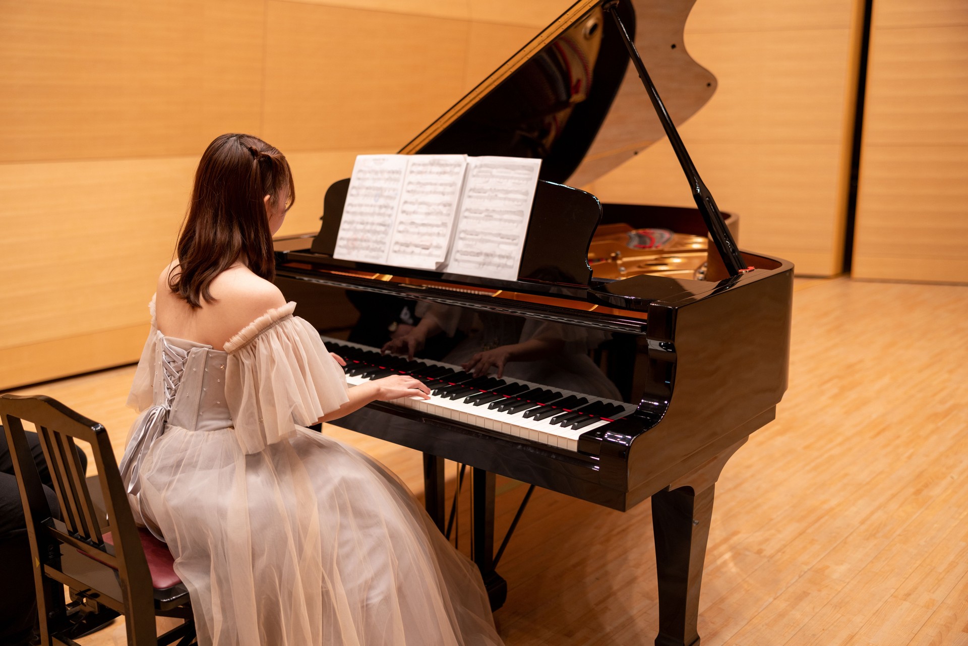 Young woman playing the piano in concert hall